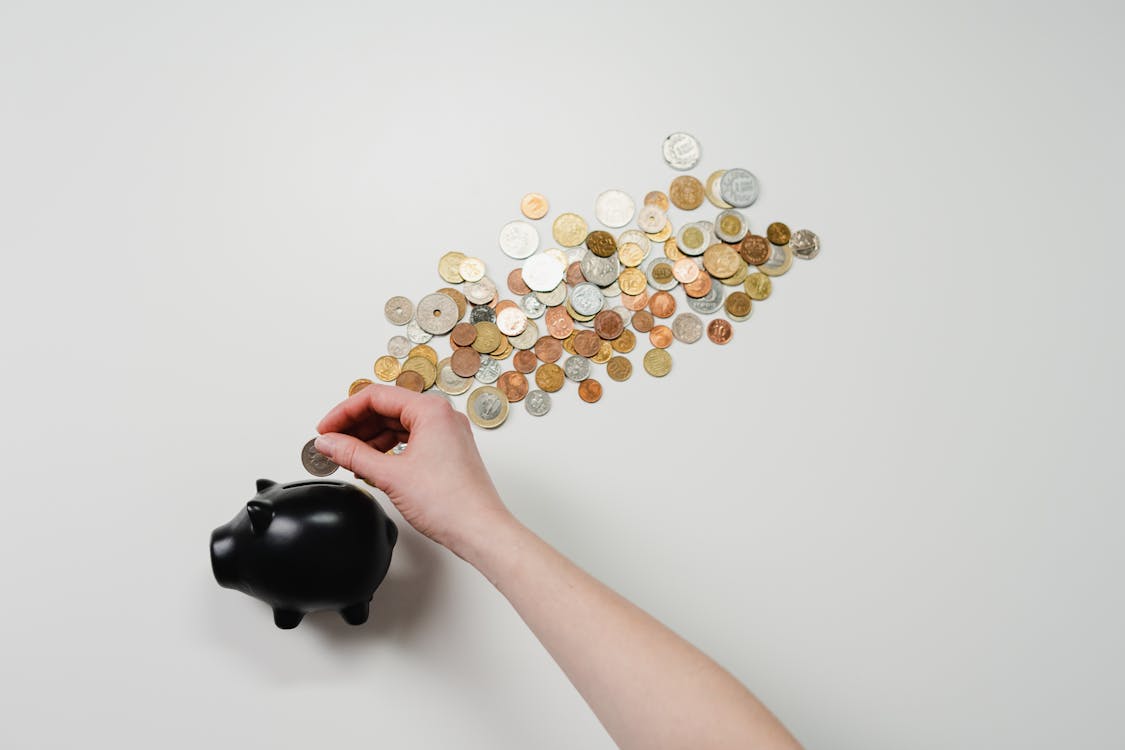 Pessoa colocando moeda em cofre, simbolizando economia doméstica