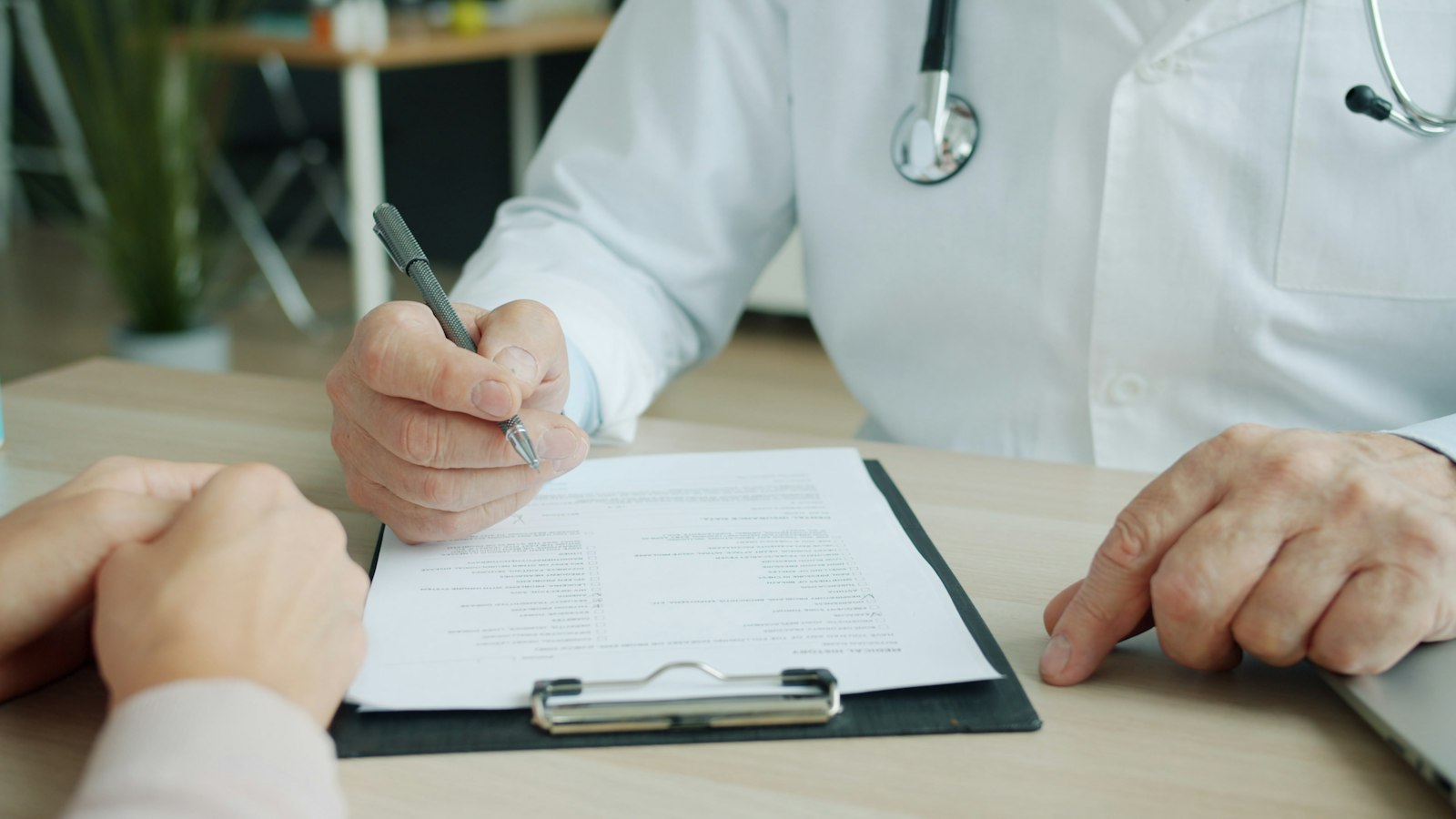Médico preenchendo um atestado na prancheta
