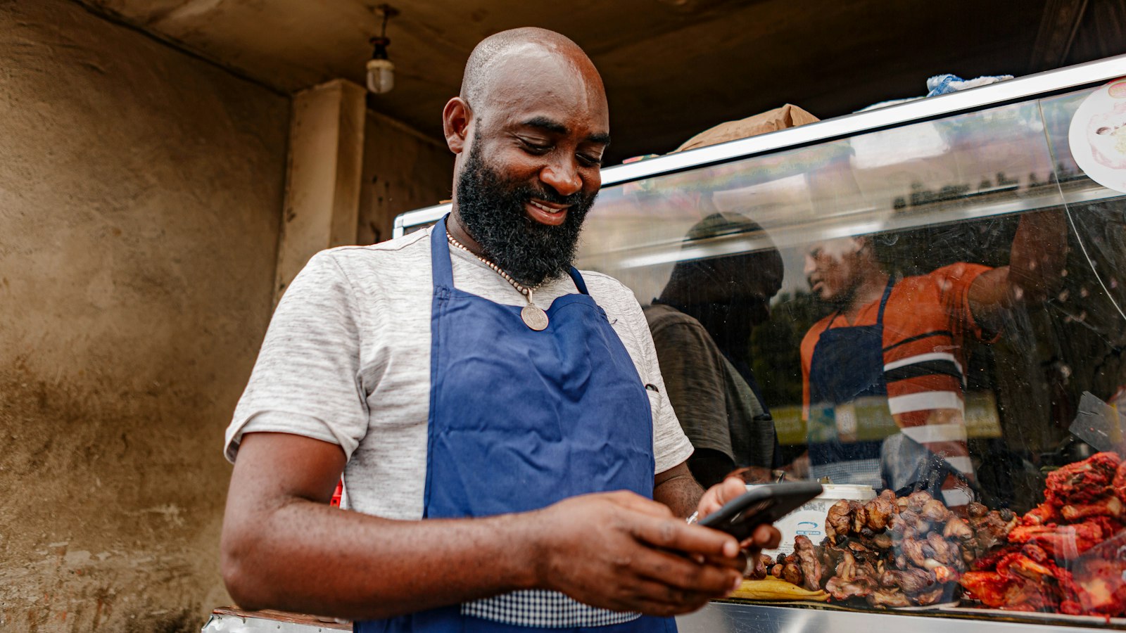 Comerciante sorridente usando o celular no balcão