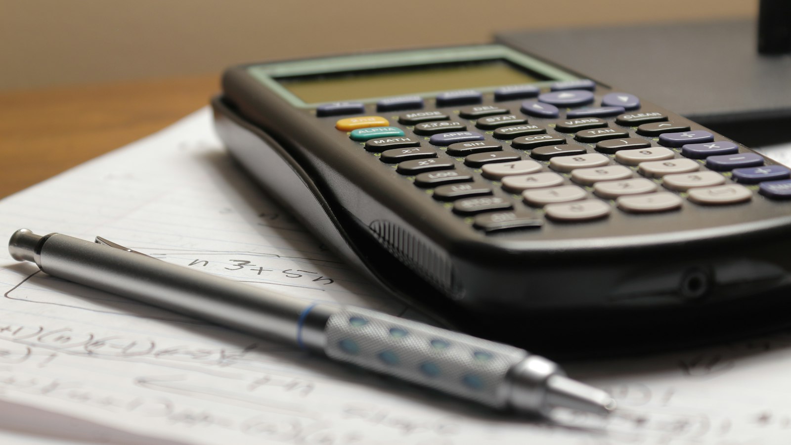 Calculadora e caneta sobre papéis