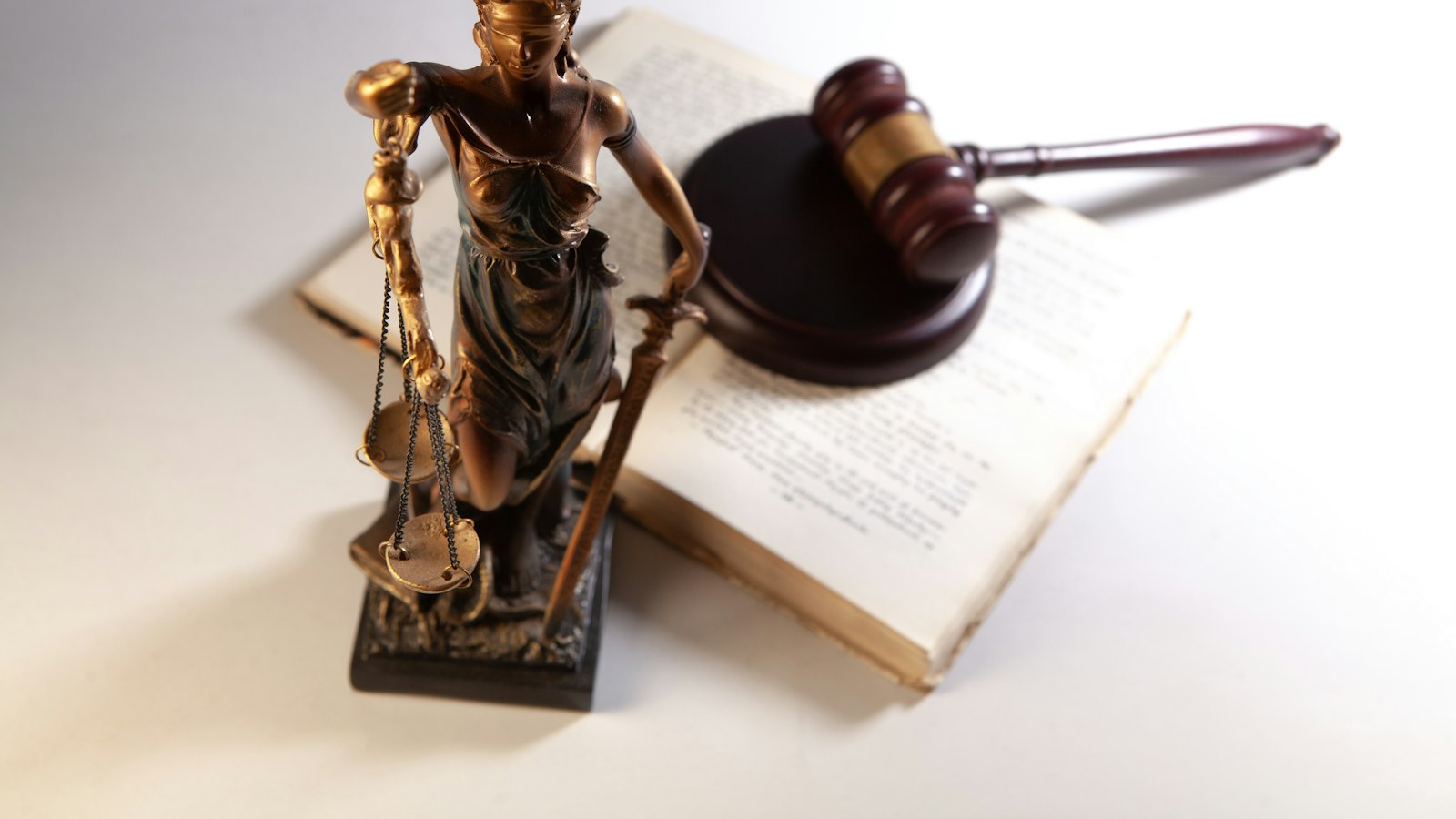 Estátua da Justiça e martelo de juiz sobre um livro