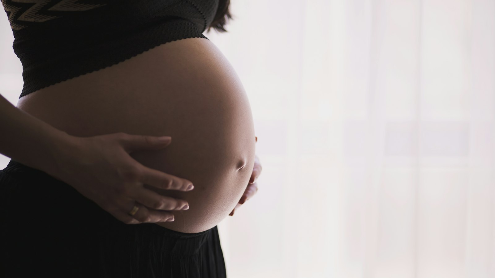 Mulher grávida com as mãos na barriga