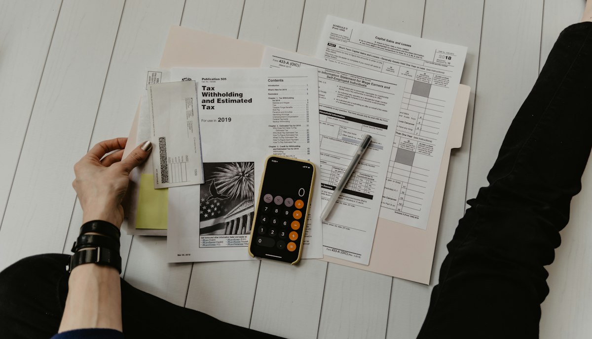 Pessoa conferindo contas e boletos com uma calculadora antes de contratar um empréstimo pessoal