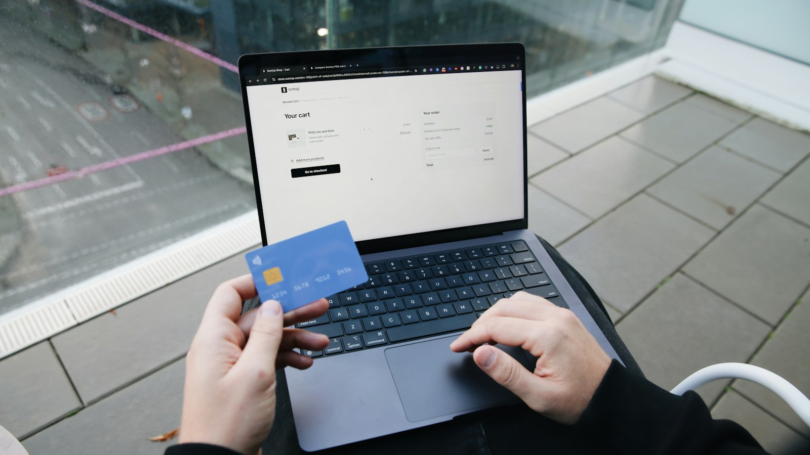 Pessoa acessando a conta pelo notebook com cartão na mão