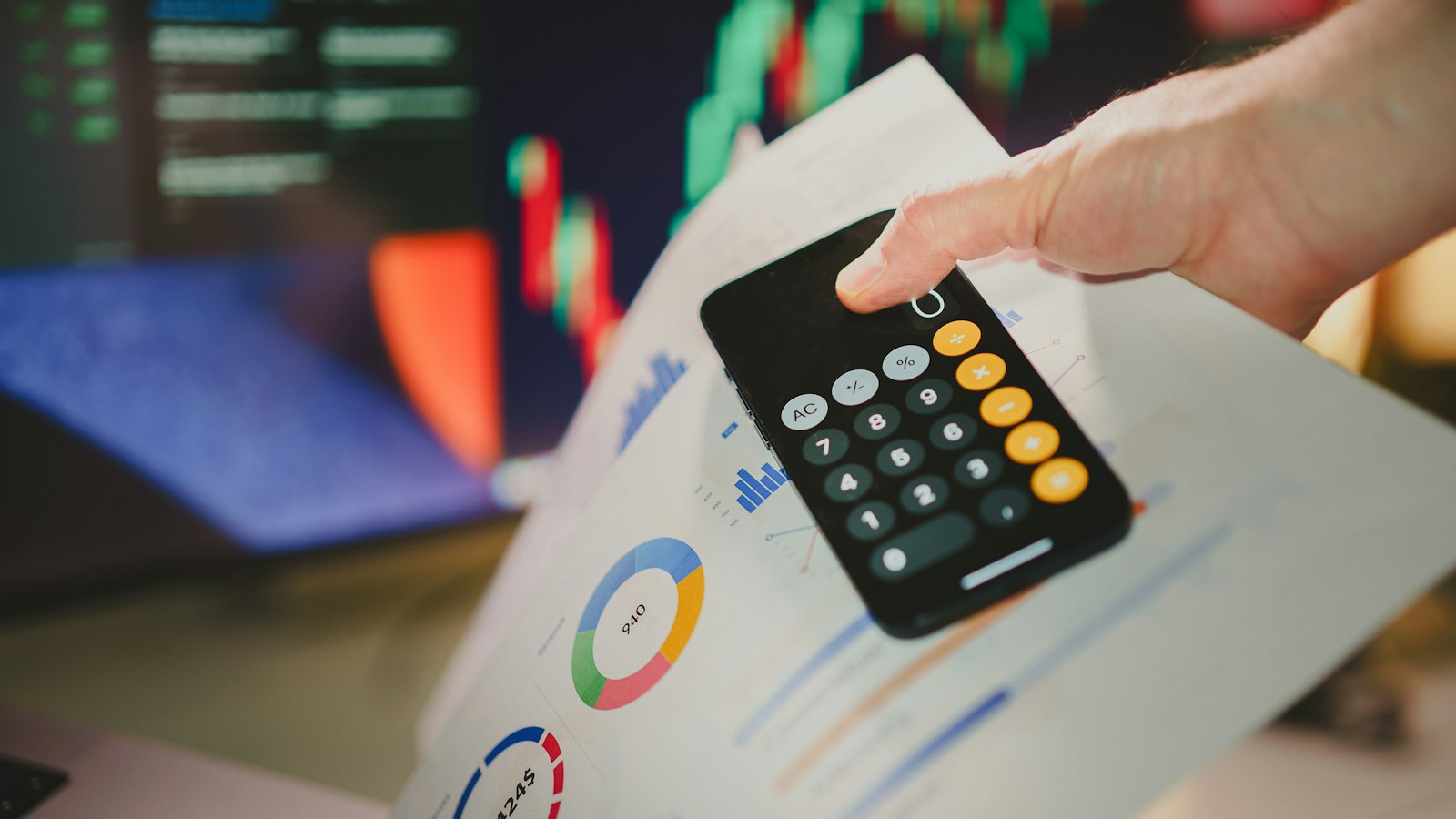 Mão usando calculadora sobre relatório com gráficos
