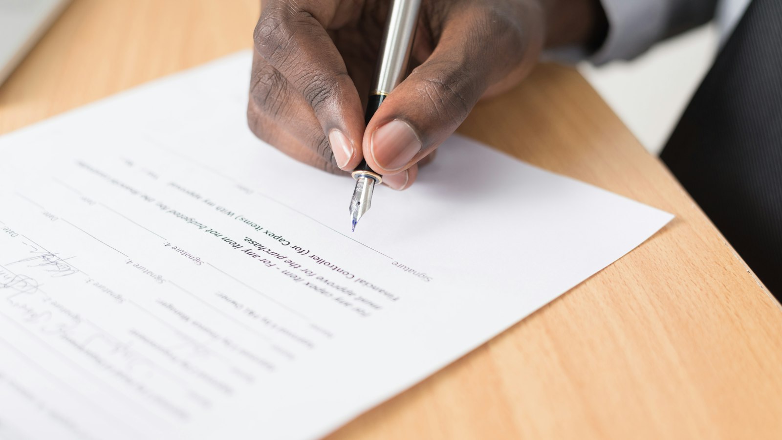Mão assinando um contrato de trabalho com caneta