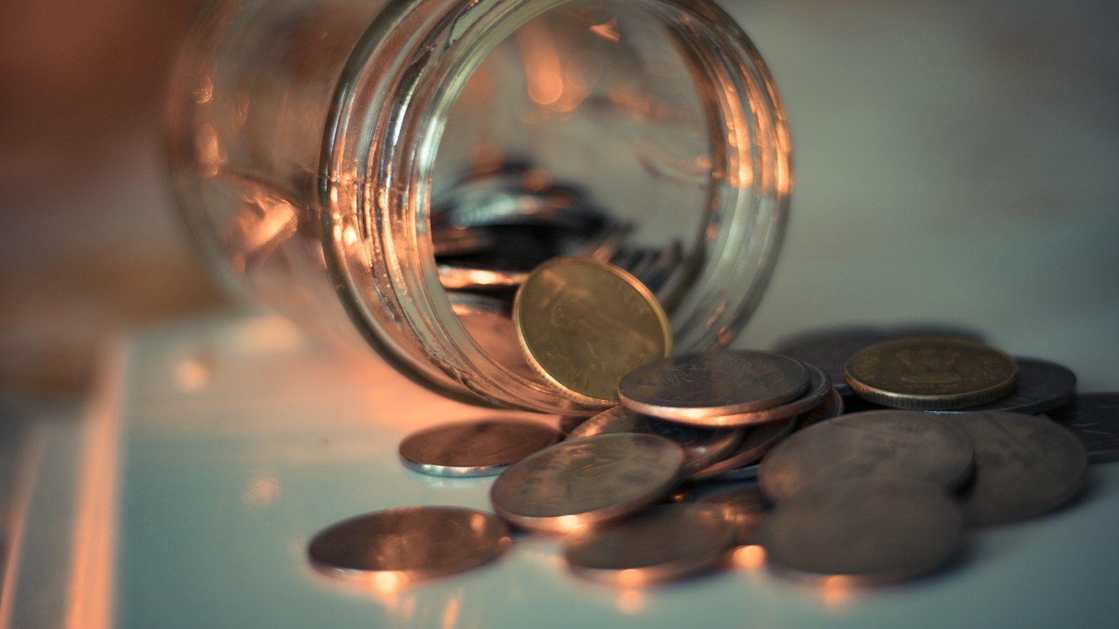 Pote de vidro com moedas sobre a mesa