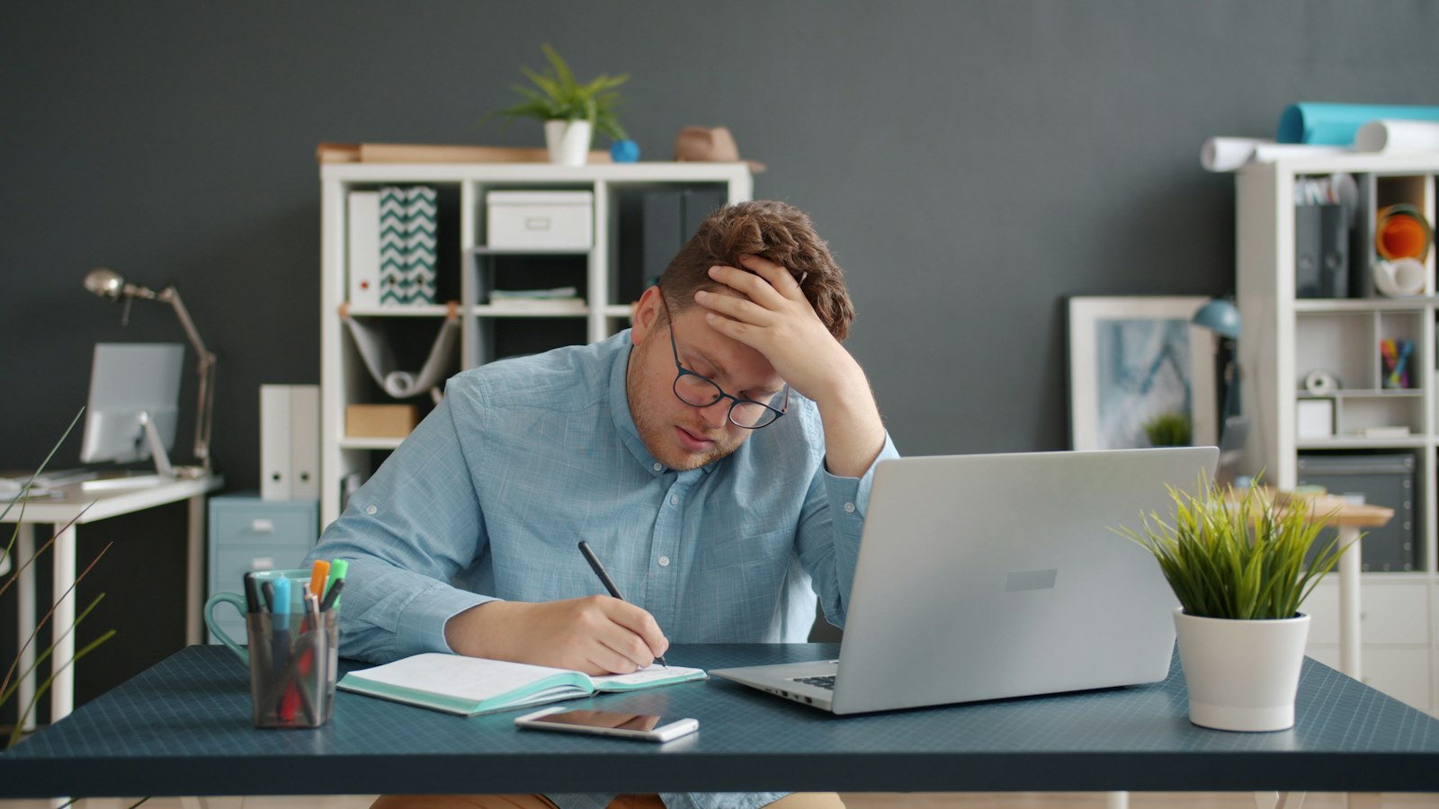 Funcionário preocupado com a mão na cabeça diante do notebook